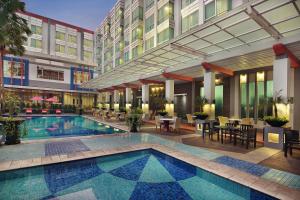 um pátio do hotel com uma piscina e mesas e cadeiras em Mercure Pontianak City Center em Pontianak