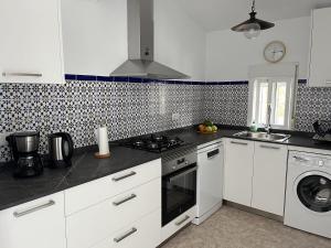 een keuken met witte kasten en een kookplaat oven bij Cortijo Pura Vida in Cómpeta