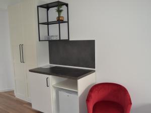 a red chair sits next to a desk with a red stool at Dom Goscinny Aurora in Dziwnówek