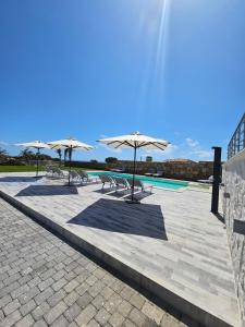 a group of tables with umbrellas and a pool at Cava Del Mar in Augusta +15 photos
