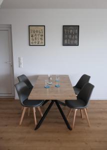 einem Holztisch mit vier Stühlen und Gläsern darauf in der Unterkunft Modernes Privathaus am See mit Highspeed-Internet in Sassenburg
