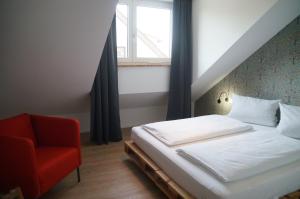 una camera con letto e sedia rossa di Hofgut Stefan a Uhldingen-Mühlhofen