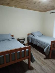 1 Schlafzimmer mit 2 Betten und Holzdecke in der Unterkunft Cabaña Refugio Alta Cordillera Tulahuén 8 personas in Piedra Lisa