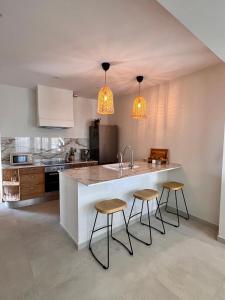 una cucina con due sgabelli e un bancone con lavandino di Renovated cinema town house in Comares a Málaga