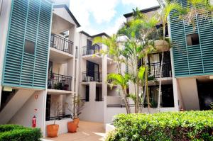 apartamentowiec z niebieskimi oknami i palmami w obiekcie Spring Hill Mews Apartments w mieście Brisbane