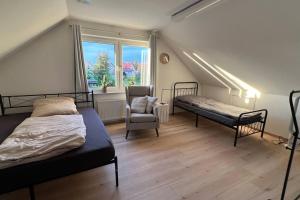 a bedroom with two beds and a chair and a window at Ferienhaus mit Seeblick in Templin