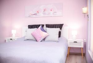 ブルガスにあるStudio Violetのベッドルーム1室(ピンクと紫の枕が入った白いベッド1台付)