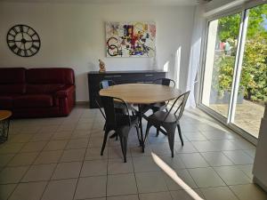 a living room with a table and chairs and a couch at MAISON avec 1 CHAMBRE dans QUARTIER RESIDENTIEL VERDOYANT CALME in Vendays-Montalivet