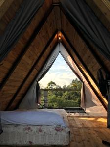 Bett in einem Zelt mit einem großen Fenster in der Unterkunft Abrigo Cantareira in Mairiporã