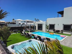 un patio trasero con piscina y una casa en VILLA KARLA en Playa Blanca