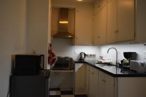 cocina con armarios blancos, fregadero y microondas en Hermoso apartamento en puerta de la Ciudad Vieja, en Montevideo