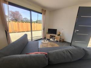 a living room with a gray couch and a tv at Les bambous - 2 logements 10min du zoo neuf-confort-famille-jeux pour enfants in Saint-Romain-sur-Cher