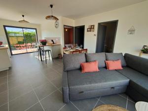a living room with a gray couch with two orange pillows at Les bambous - 2 logements 10min du zoo neuf-confort-famille-jeux pour enfants in Saint-Romain-sur-Cher