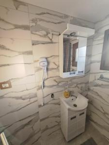 een badkamer met een witte wastafel en een spiegel bij Apartman Dača in Malo Laole
