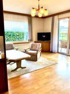 een woonkamer met een bank, een tafel en een tv bij GARDEN PARADISE - Ferienhaus mit 400m2 Garten - Nähe Ossiacher See in Villach