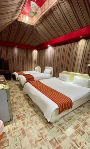 3 camas en una habitación con paredes de madera en Wadi Rum Sights Camp, en Wadi Rum