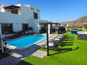 a swimming pool with lounge chairs and a house at VILLA KARLA in Playa Blanca