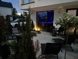 un patio avec des chaises et des tables en face d'un bâtiment dans l'établissement Axel Boutique Jacuzzi & Sauna, à Dziwnów