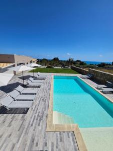 - une piscine avec des chaises et des parasols sur une terrasse dans l'établissement Cava Del Sol, à Augusta
