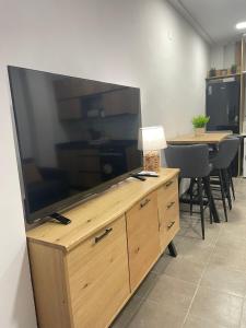 a large flat screen tv on a wooden entertainment center at UIM Mediterraneo Estudio PB San Jose Wifi in Puerto de Sagunto