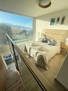 1 dormitorio con 1 cama y balcón de cristal en Miras Apartment Ushuaia en Ushuaia