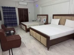 une chambre d'hôtel avec deux lits et une chaise dans l'établissement FAMIlYGUESTHOUSE KARACHIAIRPORT, à Karachi