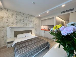 a bedroom with a bed and a vase of flowers at Sunshine Apartments Batumi Lux in Batumi