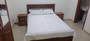 un lit avec des draps blancs et des oreillers dans une chambre dans l'établissement AMDI Appartement, à Dakar