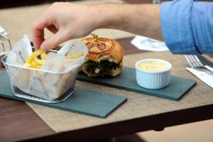 a person reaching for a sandwich and french fries on a table at Intercity São Paulo Ibirapuera in Sao Paulo