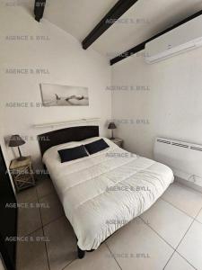 ein Schlafzimmer mit einem großen Bett mit einem Plakat an der Wand in der Unterkunft Résidence Héliovillage - Maisons & Villas pour 4 Personnes 804 - Naturiste in Cap d'Agde