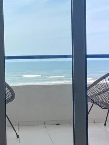 a view of the ocean from a room with two chairs at Apartamento frente mar in Praia da Vieira