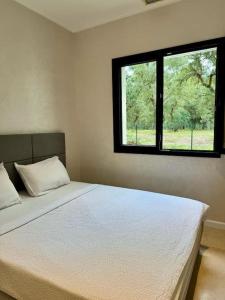 1 dormitorio con 1 cama blanca grande y ventana en Magnifique Villa neuve avec piscine chauffée, en Labenne