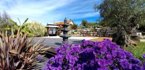 a fountain in a garden with purple flowers at Un parfum de Thaïlande, ressourcement et massages in Curemonte