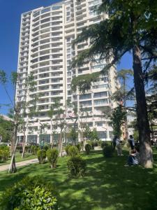 un gran edificio blanco con gente sentada en un parque en Tbilisi Luxury apartment, en Tiflis