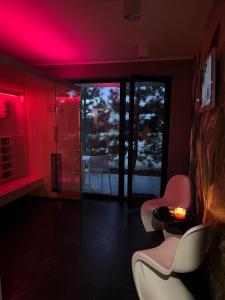 Zimmer mit roter Beleuchtung sowie einem Tisch und Stühlen in der Unterkunft Axel Boutique Jacuzzi & Sauna in Dziwnów
