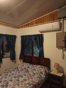 Schlafzimmer mit einem Bett mit blauen Vorhängen und einem Fenster in der Unterkunft Casa de campo en la playa in La Cruz