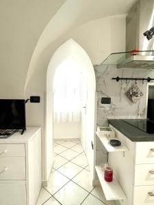 eine weiße Küche mit einem Torbogen und einem Fenster in der Unterkunft casa Alkamà in Castellammare di Stabia