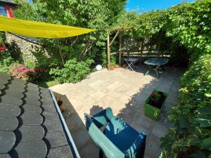 a patio with two blue chairs and a yellow umbrella at En pleine nature cantalienne et au calme village , Maison confortable et spacieuse pour 9 pers in Vezels-Roussy +16 photos
