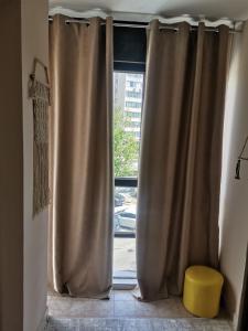 a window with curtains and a yellow stool in a room at DiV 3 in Novi Sad +2 photos