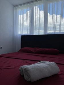 Bett mit einem Handtuch, das vor einem Fenster liegt in der Unterkunft CozyApartment in Pristina