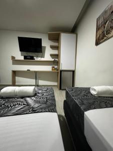 a room with two beds and a flat screen tv at HOTEL PISO 12 in Bello