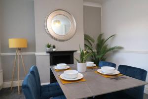 a dining room table with blue chairs and a mirror at 2 Bedroom Characterful House in Lancaster