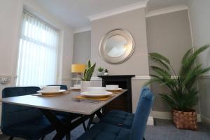 a dining room table with blue chairs and a mirror at 2 Bedroom Characterful House in Lancaster