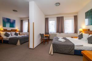 a hotel room with two beds and a chair at LH Hotel Mědínek Old Town in Kutná Hora