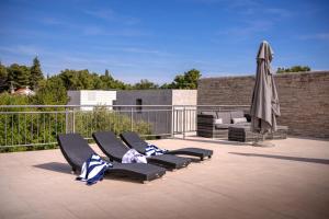 a group of lounge chairs and an umbrella on a patio at Villa Rajski Dvor in Bol