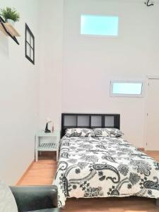 1 dormitorio con 1 cama con edredón blanco y negro en Loft con baño y cocina privados, en San Sebastián de los Reyes