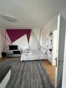 ein Schlafzimmer mit einem Bett mit einer lila Wand in der Unterkunft Апартаменти Уют in Plowdiw