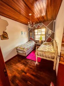 1 dormitorio con 2 camas y lámpara de araña en Lar Loudge Montanhes, en Campos do Jordão