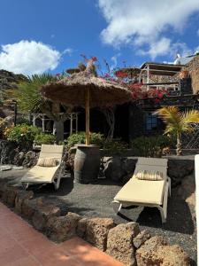 Dos sillas y una sombrilla frente a una casa. en Castillo Lanzarote Villa Bailey - Luxury Villa - Pet friendly with heated Pool, en La Asomada