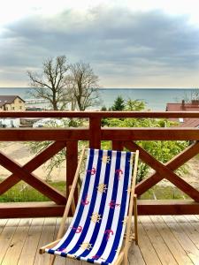 uma cadeira de praia sentada num deque com vista para a praia em Dom Wakacyjny Klifowa 1 em Mechelinki